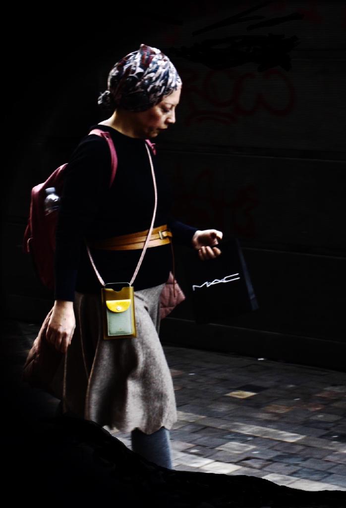 Το μοναδικό φωτεινό πλάσμα μέσα σ’ ένα σκιώδες κομμάτι στο Μοναστηράκι που είναι εγκλωβισμένο ανάμεσα σε δύο χαλύβδινης κατασκευής όγκους. Τα ανθώπινα μάτια αναγνωρίζουν πιο εύκολα το φως εκεί που ο φωτογραφικός φακός βρίσκει μόνο σκοτάδι. Το φως της απαθανατισμένης διέσχιζε το σκοτάδι όπως η μικροσκοπική ηλιαχτίδα τρυπάει το αλαμπές δωμάτιο. Είναι ο ωραίος ο ενθουσιασμός για λίγη ζωή ακόμη. Η ανηδονία του καταθλιπτικού μπορεί να τον προικίζει με σοφία, του αφαιρεί όμως τις περισσότερες συγκινήσεις του.